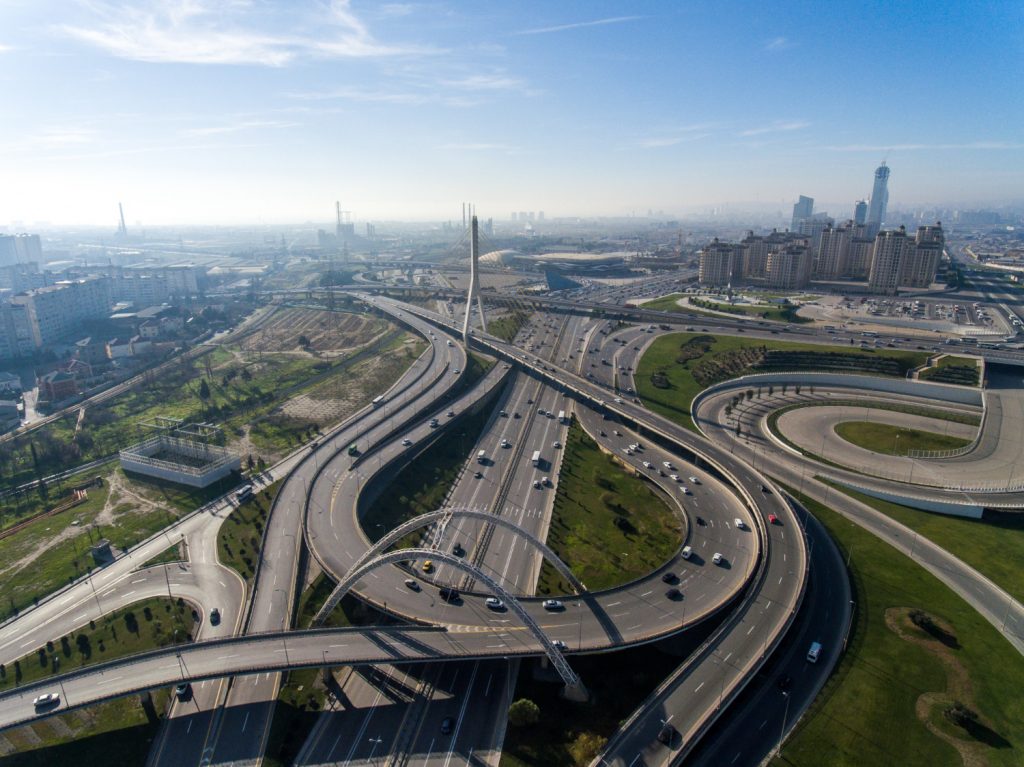 Imagen que muestra una infraestructura de carreteras con una ciudad al fondo, explicando como pueden contribuir al desarrollo sostenible.